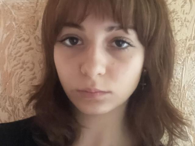 LeomaHaq has brown hair, straight bangs, and a neutral expression. She has small tits, light skin, and black eyeliner. Her lips are slightly parted. She's wearing a black top.