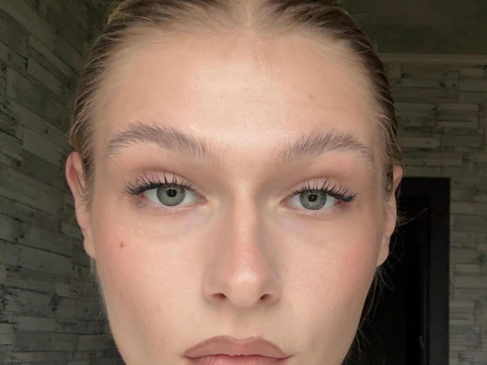 Le visage de VidaZamborsky, avec sa peau pâle, ses yeux verts, ses sourcils châtains clairs, ses longs cils et ses lèvres légèrement entrouvertes. Ses cheveux blonds sont tirés en arrière. Elle a une petite tache rouge sur sa joue..