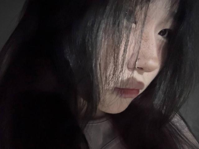 JungMcgranor's face with long, dark, messy hair covering one eye, pale skin, and red lips in a soft, shadowy light. Her expression is slightly serious, and she looks to the side.