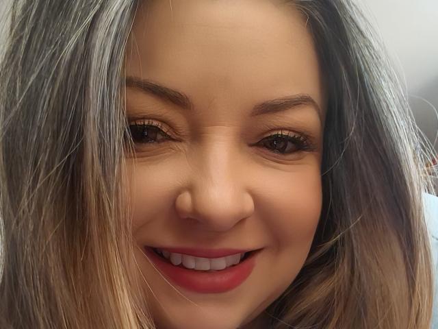 NatalyHami's face, showing her smiling nose, red lips, brown eyes, and blonde hair with gray highlights. Her ass isn't visible, just her face.