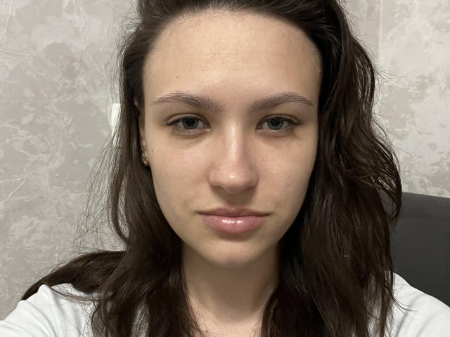 IsobelStaehle tiene un rostro con labios naturales y brillantes, cabello ondulado castaño y piel clara con un maquillaje sutil. Lleva una camisa blanca y mira directamente a la cámara..