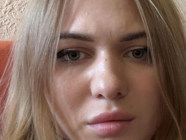LynneBernecker's face, showing her pouty, slightly glossy pink lips and green eyes, with her blonde hair partially covering her forehead. Her nose is small and her skin is smooth.