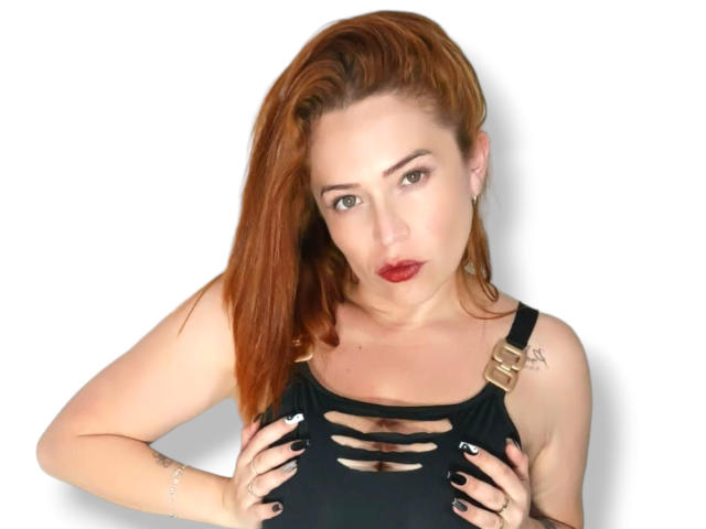 ImEmilyHanks with red hair, black cut-out top, hands on her tits, red lipstick, white background, black nail polish, and a tattoo on her right shoulder.