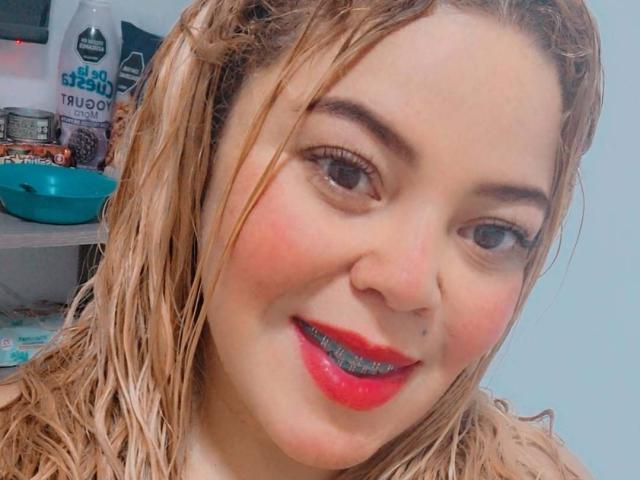 Sharicke69 ha i capelli biondi, con riflessi dorati, rossetto rosso e rossetto azzurro, e sorride con le guance rosate, occhi marroni e un piercing al naso. Il suo seno è parzialmente visibile..