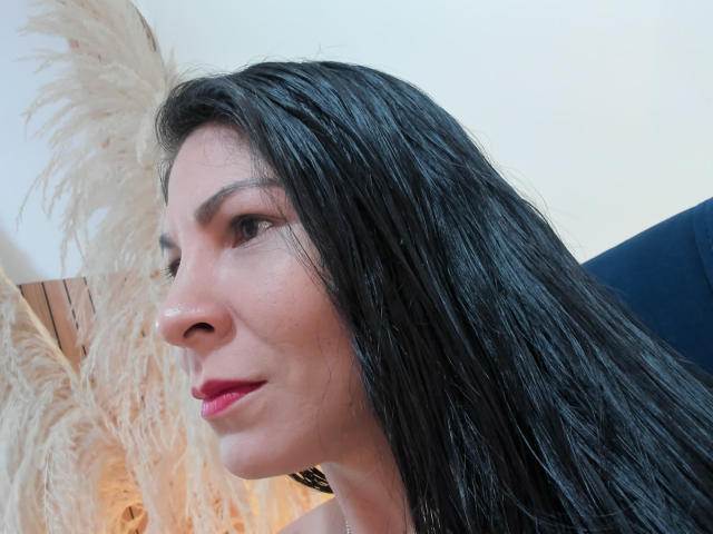EliseBell has wet, black hair, a small nose, and pink lipstick, looking to the left with a slight smile. She's wearing a black top. Her ass is not visible.