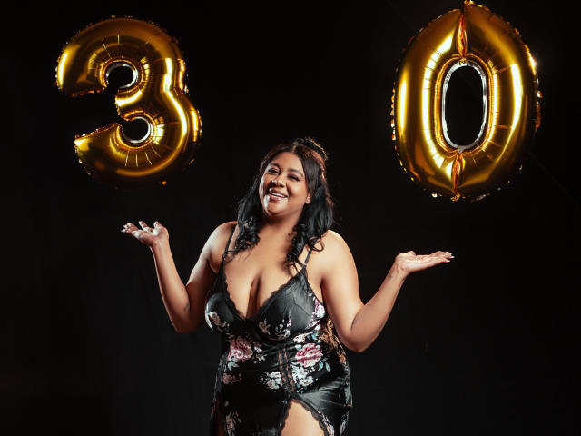BiancaForest con grandes senos, vestido floral negro, sonriendo, manos levantadas, globos dorados con el número 30, fondo oscuro, cabello negro rizado, sexy, segura de sí misma, celebratoria, foto de cuerpo entero..