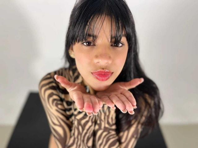 JeanneLacroix with black zebra-pattern shirt, hands out, red lipstick, and dark hair, looking up with a slightly open mouth, showing her pouty lips and cute ass.