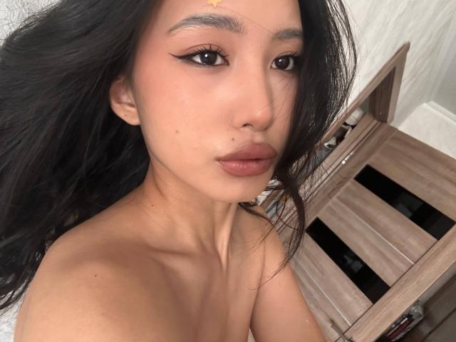 LeonilaSeewald has dark, wavy hair, brown eyes, and full lips with a small beauty mark on her left cheek. Her bare shoulders are visible. She's wearing a gold forehead dot.