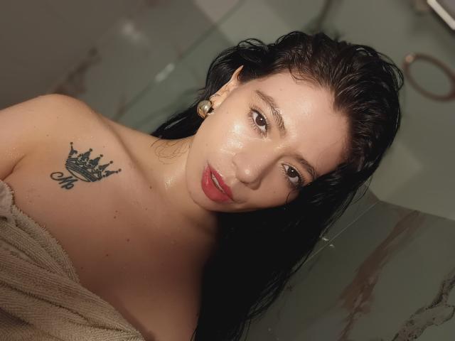 Linda Mancini ha i capelli neri e umidi, la pelle luminosa e il rossetto rosso. È senza maglietta, con un asciugamano che le copre il seno, mostrando un tatuaggio a forma di corona sulla spalla destra..