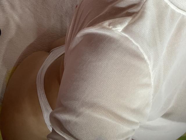 La maglia a rete bianca di SaritaCaramelo è tirata su, rivelando il suo sedere scoperto e la biancheria intima bianca. La sua pelle è chiara e la trama della maglia è a coste..