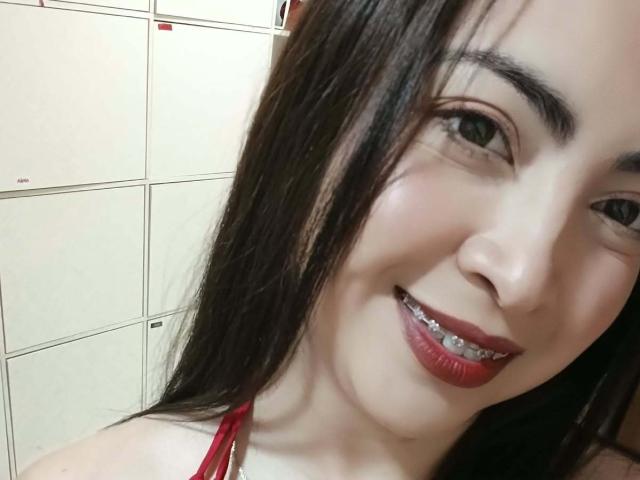 AlanaWest has long black hair, dark red lipstick, and metal braces. Her fair skin and green eyes are visible in a selfie with a slight smile.
