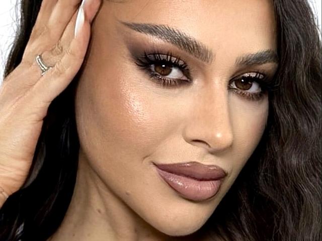 El rostro de CristalSky, con ojos marrones, cejas gruesas, un labial marrón brillante y un anillo en su mano izquierda, y cabello oscuro y ondulado que le toca la cabeza..
