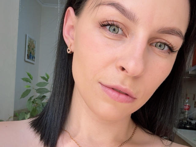 EmmaNoa ha la pelle chiara, gli occhi verdi, i capelli neri e lisci, piccoli orecchini dorati e labbra rosate, indossa una collana dorata e ha un'espressione neutra. Il suo seno non è visibile..