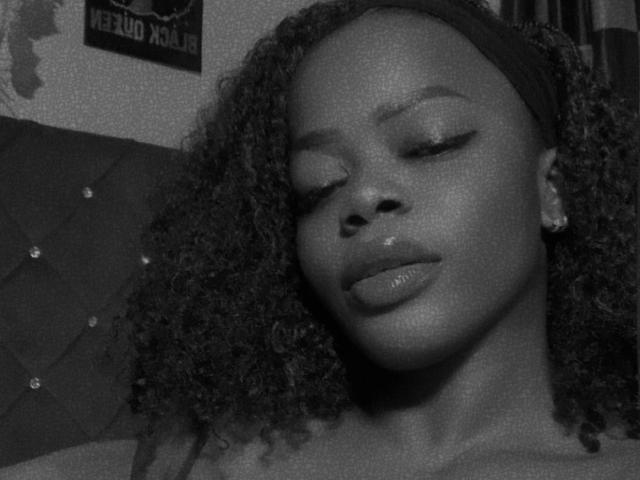 Black-and-white photo of SexyKayla-hot with curly hair, eyes closed, and glossy lips, wearing a headband, showing smooth, dark skin and a relaxed, beautiful face.
