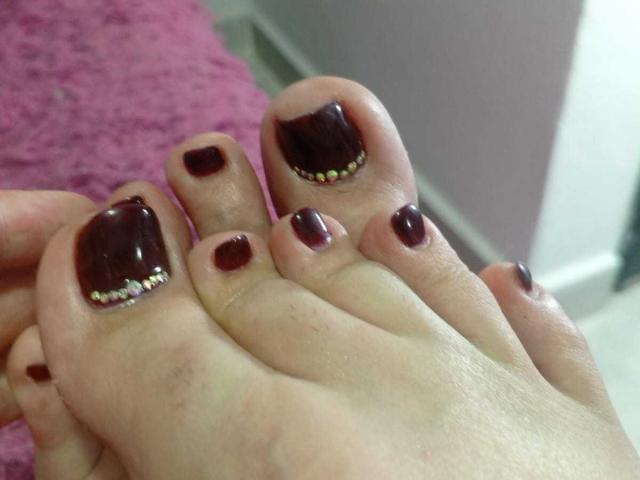I piedi di ShariTheBigCock sono dipinti con uno smalto rosso scuro, lucido e liscio, con minuscole palline di glitter bianche e rosa sulle punte delle dita più grandi..