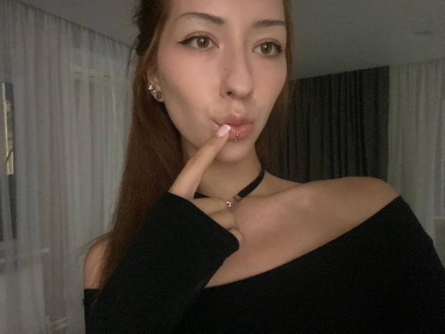 MarylnWerntz with pouty lips, finger gently touching bottom lip, brown eyes, black off-shoulder top, long brown hair, small earrings, fair skin, sexy, cute.
