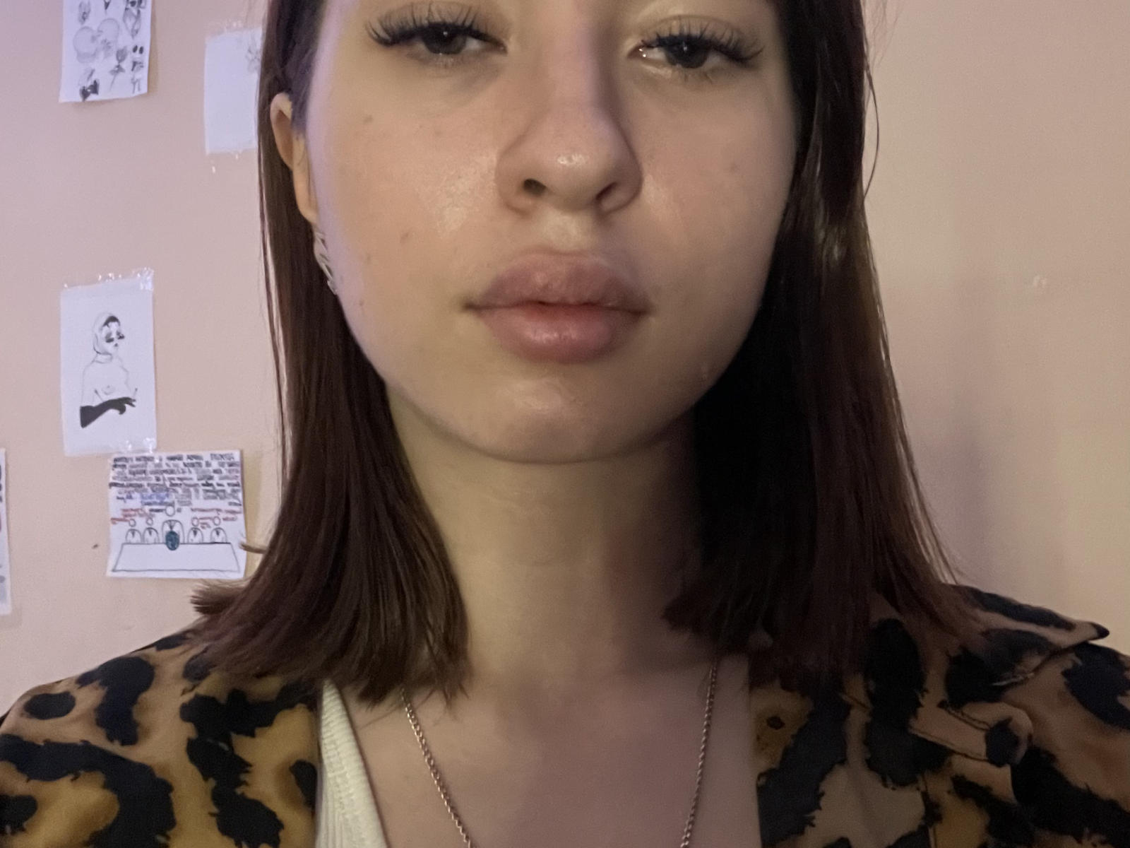 JoyaZiemba tiene una expresión neutra, con labios ligeramente fruncidos, cabello castaño liso hasta los hombros, y lleva una camisa con estampado de leopardo. Tiene una nariz pequeña y un maquillaje sutil..