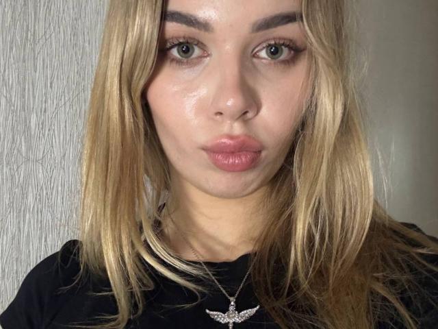 KylaHemeke heeft een glanzende, bezwete huid, blond haar, groene ogen en samengeknepen, roze lippen. Ze draagt een zwart shirt en een zilveren ketting met een vleugel..