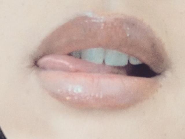Les lèvres brunes et brillantes de Lincysexx sont légèrement entrouvertes, et sa langue rose effleure de manière suggestive la partie supérieure de ses dents blanches. Ses lèvres ont un aspect brillant et humide..