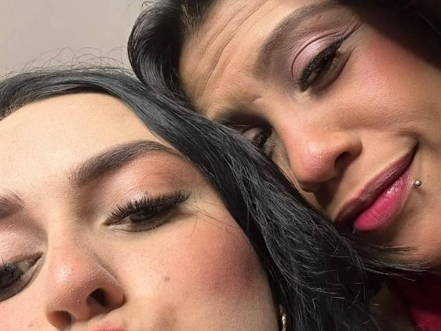 ElizabethAndEliana's faces are close together, both with dark hair and pinkish-brown skin. ElizabethAndEliana on the right has a lip piercing and is smiling. ElizabethAndEliana on the left.
