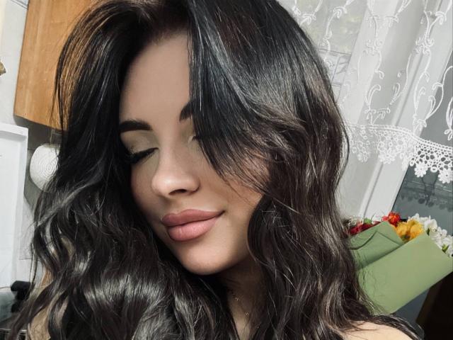 Giuseppina, avec ses cheveux noirs ondulés, ses yeux fermés et ses lèvres roses pulpeuses, sourit doucement. Son nez est petit et sa peau est claire. Elle a un air séduisant et attrayant..