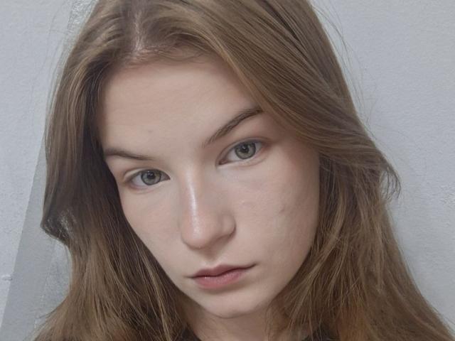 Justine Hasenfratz ha i capelli castano chiaro, mossi, gli occhi verdi e un viso pallido, leggermente arrossato, con labbra piccole, rosa e leggermente dischiuse. Le sue sopracciglia sono sottili e naturali..