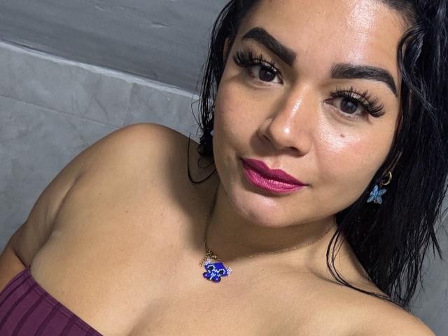 Antonella Bellas ha i capelli neri e umidi, gli occhi marroni, le sopracciglia folte, il rossetto rosa e indossa una canottiera viola, una collana con un fiore blu e orecchini a forma di farfalla blu..
