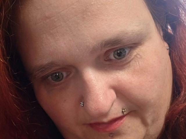 Hotsunny20-sex has pale skin, green eyes, and red hair. She's got nose and lower lip piercings, with a small nose stud and a septum piercing.