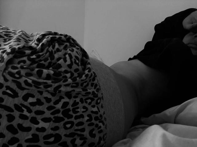 MissSunnyShine's leopard-print pajamas are pulled down, exposing her flat, toned belly. Her black top is raised, showing her side. A white bedsheet is partially visible.