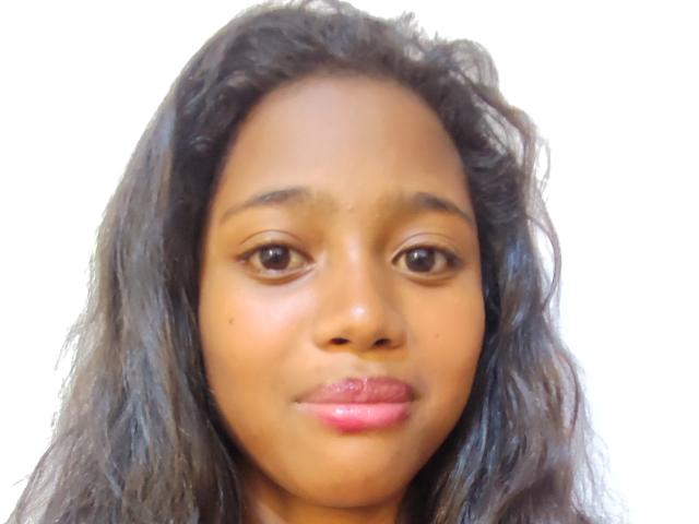 BetyBoobs has medium brown skin, curly black hair, brown eyes, and pink lips with a slight pout. She's staring forward with a neutral expression.