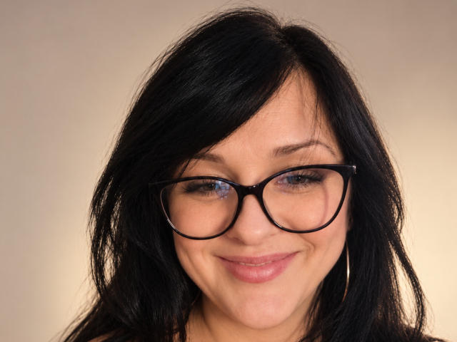 OxiLover has black hair, blue eyes, and is wearing black glasses with a slight smile. She has light skin and is looking directly at the camera.