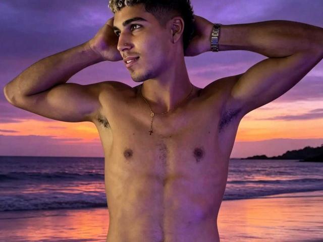 SantiaGodiazz, shirtless, with hands in curly blonde hair, smiling, muscular, tan skin, small nipples, armpit hair, gold necklace, wristwatch, sunset beach background, purple-orange sky.