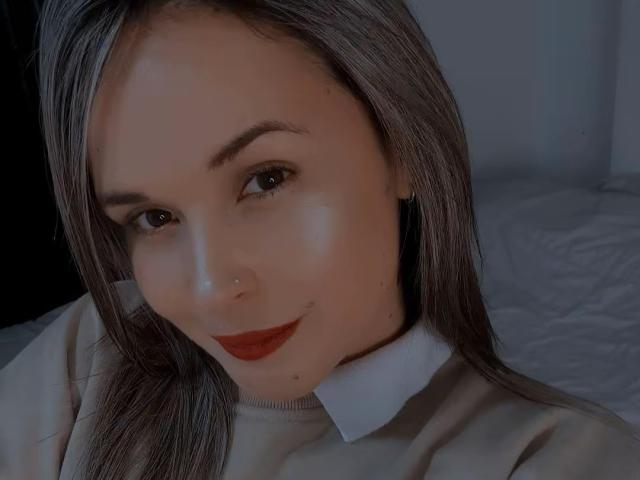 WendySchulz has shiny, straight gray hair, a cute nose ring, and red lipstick on her slightly shiny, smooth face. She's wearing a white shirt with a collar.