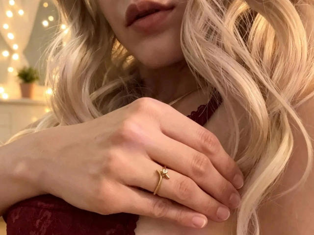 LaurenSommer-haar hand met een gouden ring, rustend op haar borst, over haar borsten, in een rode kanten beha, met blond golvend haar en licht open roze lippen..