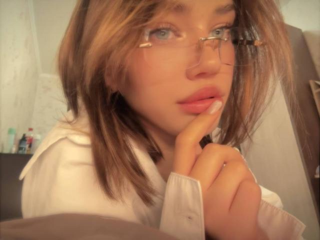 AlyceFujino with glasses, brown hair, blue eyes, and pink lips, slightly biting her finger, wearing a white shirt, looking up with a soft, innocent expression.