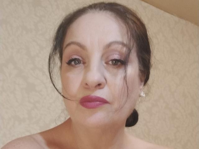 Emerald ha la pelle chiara, i capelli castano scuro raccolti in un'acconciatura disordinata, ombretto rosa, eyeliner nero, rossetto rosa e piccoli orecchini di diamanti, con un'espressione neutra..