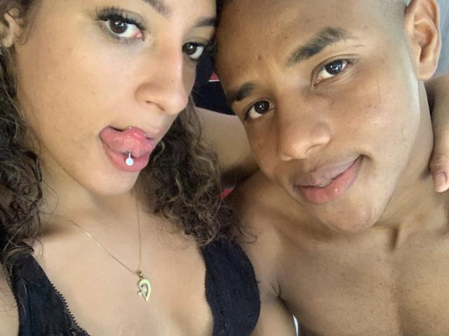 CristalAndRichard tiraram uma selfie: os lábios rosados e curvados de Cristal mostram uma piercing de língua prateada, ela veste uma blusa de renda preta e um colar de ouro, enquanto Richard tem a cabeça raspada, olhos castanhos e a língua de fora..