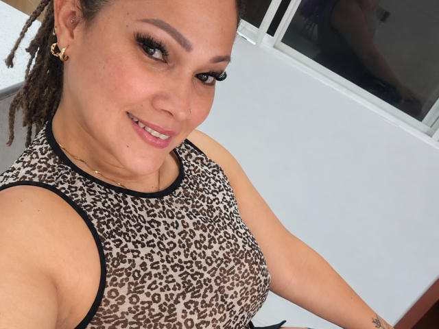 Vianca Castellanos, con la pelle olivastra, gli occhi marroni e i capelli ricci raccolti in trecce, sorride alla fotocamera, indossando una canottiera a stampa leopardo che mette in mostra il seno, e orecchini a cerchio dorati..