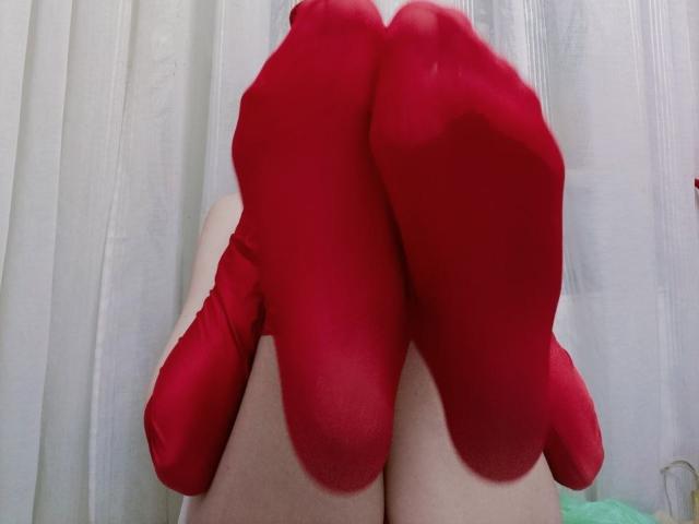 WollyMolly's red socks cover their feet and lower legs, with the soles facing the camera, showing a bit of pale skin above the socks.
