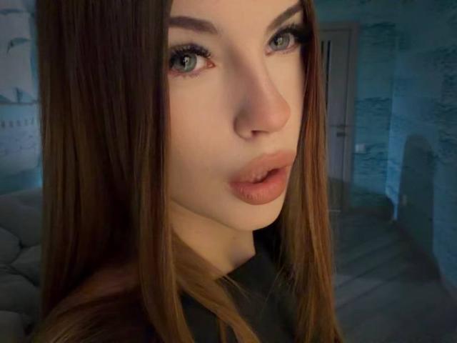 Il viso di Bethany Sandhoff in un selfie, con capelli castani, occhi verdi e labbra piene. Il suo naso è centrato e indossa una camicia scura. Le sue labbra sono leggermente socchiuse..