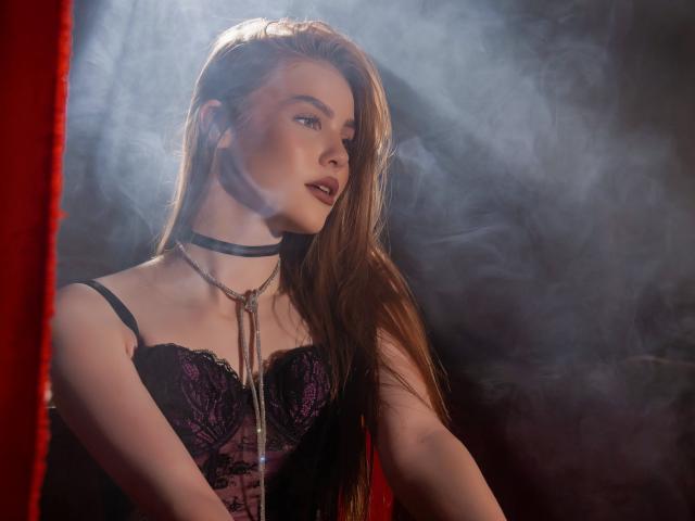 MargoKoli with long brown hair, wearing black lace corset and leather choker, chain around neck, looking to the side, red curtain partially visible, smoke in background.