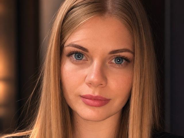 Pannia has blue eyes, straight blonde hair, and pink lips. Her ass is not visible, but she's a pretty, cute bitch with a serious expression.