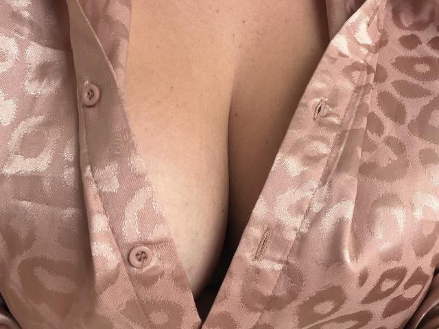 Dinastiia's boobs are covered by a pink, leopard-print satin robe, with the robe partially open to reveal her cleavage and a button on the robe.