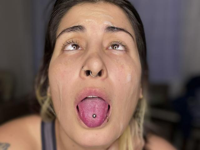 NyxVale ha un anello al naso, la lingua è fuori con un piercing ed è ricoperta di sperma. I suoi capelli biondi sono sciolti e i suoi occhi sono rivolti verso l'alto..