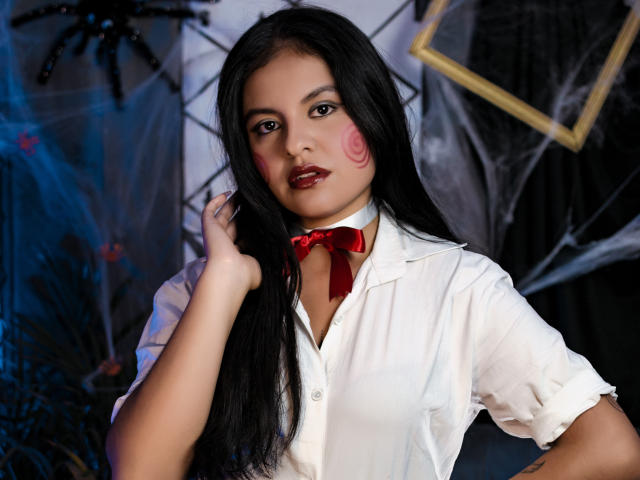 AlessiaVeega with long black hair, red lipstick, pink cheeks, white shirt, red bowtie, hand in hair, sexy, cute, attractive, medium tits, soft light, dark blue and black background.