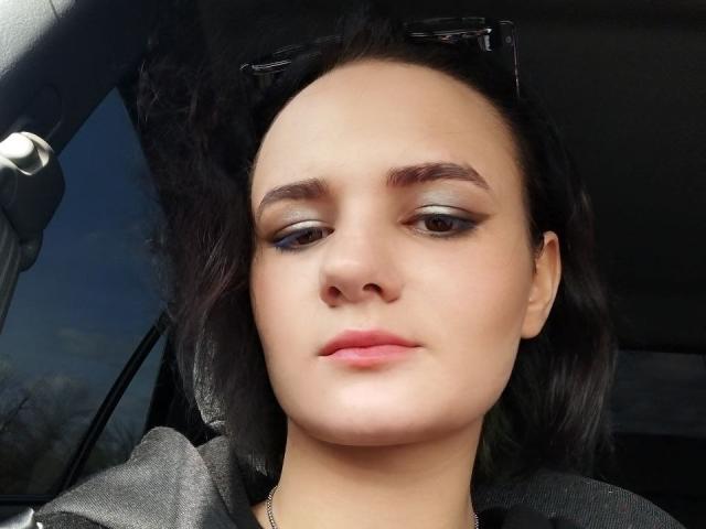 TreenaVisosky has light brown skin, dark wavy hair, and subtle makeup with silver eyeshadow. She's wearing a black shirt, and sunglasses are on her head. Her lips are slightly pink.