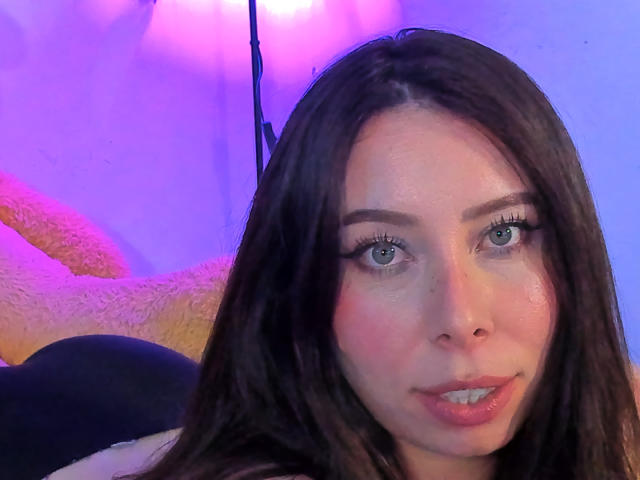 JennyLawry with shiny blue eyes, long brown hair, and slightly parted pink lips, looking directly at the camera. Her nose is small and she has a gentle smile.
