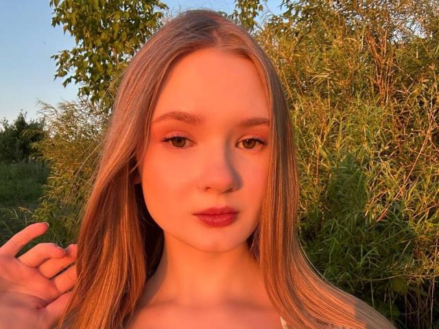 Solange Gulsvig a de longs cheveux blonds et lisses, une peau claire et des lèvres pleines et roses. Elle regarde l'appareil photo avec un sourire discret, et sa main est près de sa tête..