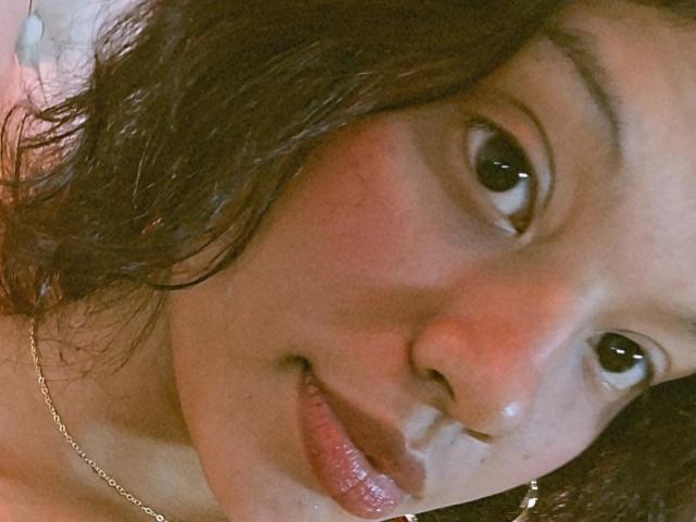 PauletteDelacroix ha un viso carino, con occhi marroni, capelli scuri ondulati, guance rosate e un leggero sorriso che mostra labbra lucide. Indossa una collana d'oro..