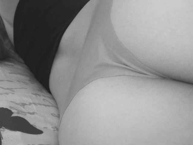 CherryBuchel's ass in tight, light-colored panties, with a black top above. Black and white photo, showing her round, smooth butt and slight waist curve.